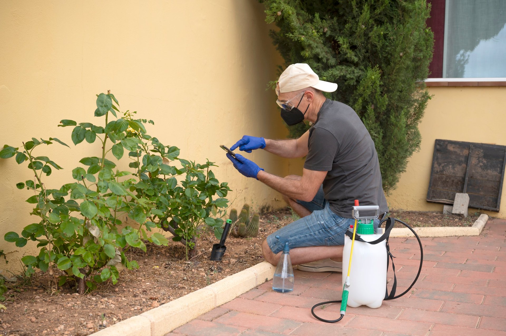 Pest control professional in protective gear treating a property